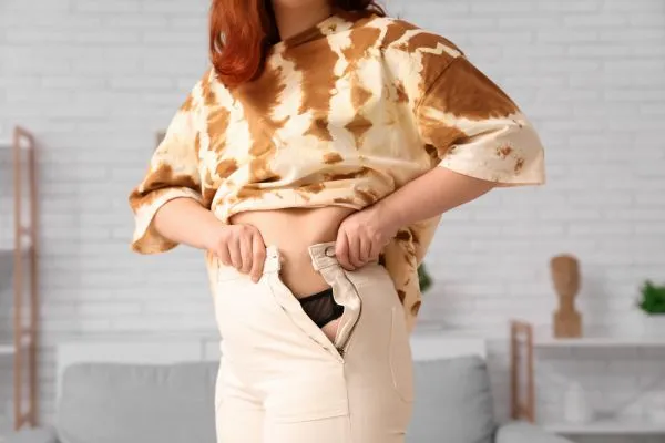 Image of woman trying to do her trousers up after pregnancy weight gain Shropshire